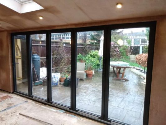 Extension Kitz Case Study - View from inside with Plastering, skylights and glazing done and bi-fold doors in place.